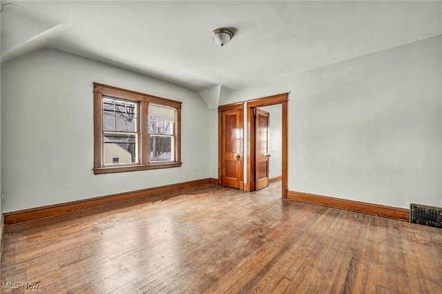 spare room with vaulted ceiling and light wood-type flooring