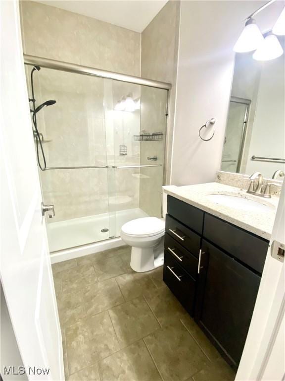 bathroom with vanity, toilet, and a shower with shower door