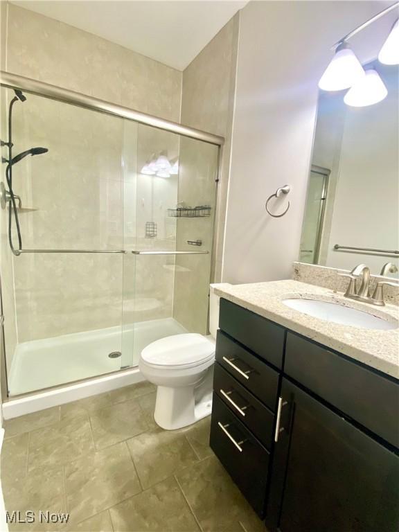 bathroom featuring vanity, an enclosed shower, and toilet