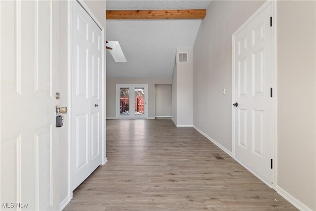 interior space featuring lofted ceiling with skylight and light hardwood / wood-style flooring