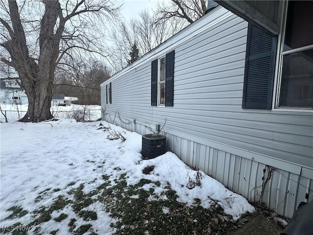 snow covered property with central air condition unit