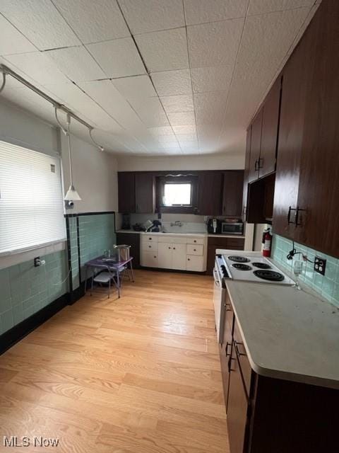 kitchen with dark brown cabinetry, decorative light fixtures, light hardwood / wood-style floors, and white range with electric cooktop