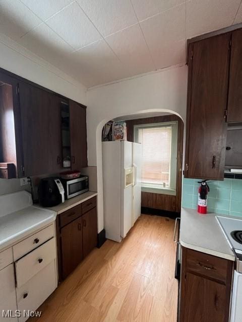 kitchen with tasteful backsplash, white refrigerator with ice dispenser, electric range, light hardwood / wood-style floors, and dark brown cabinets