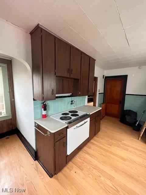 kitchen with dark brown cabinets, decorative backsplash, and light hardwood / wood-style flooring