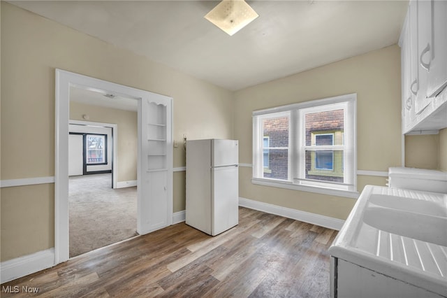 kitchen featuring white refrigerator, a healthy amount of sunlight, white cabinets, and light wood-type flooring