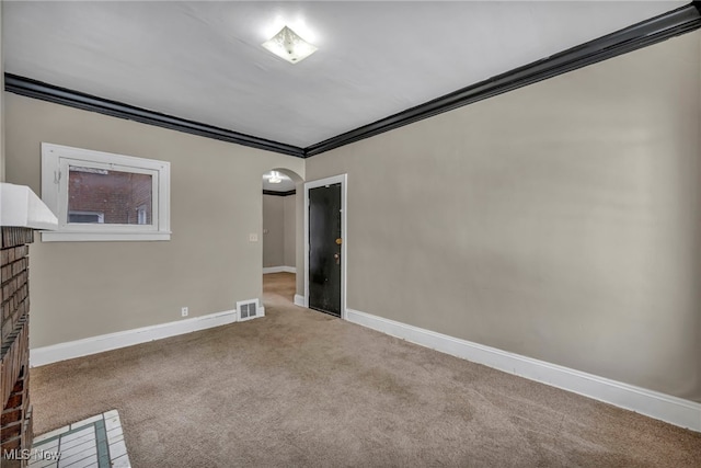 empty room with a fireplace, ornamental molding, and carpet flooring