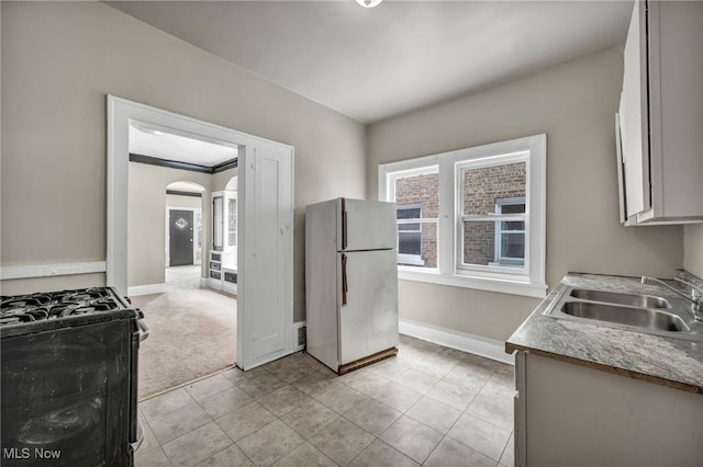 kitchen with white refrigerator, sink, light colored carpet, and range with gas cooktop