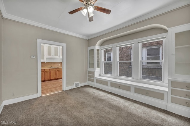 carpeted empty room with crown molding and ceiling fan