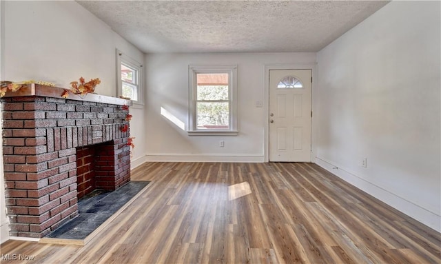 entrance foyer featuring dark wood-type flooring, a fireplace, and a textured ceiling