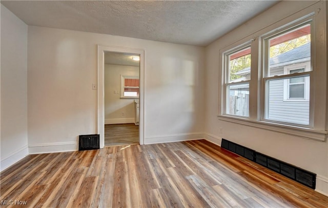 unfurnished room featuring light hardwood / wood-style floors and a textured ceiling