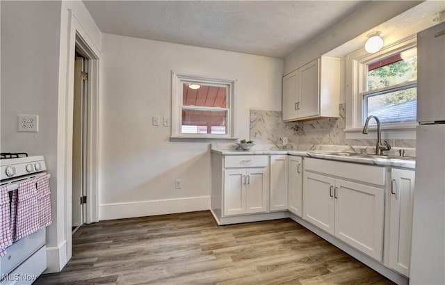 kitchen featuring sink, white cabinetry, tasteful backsplash, light hardwood / wood-style flooring, and white appliances