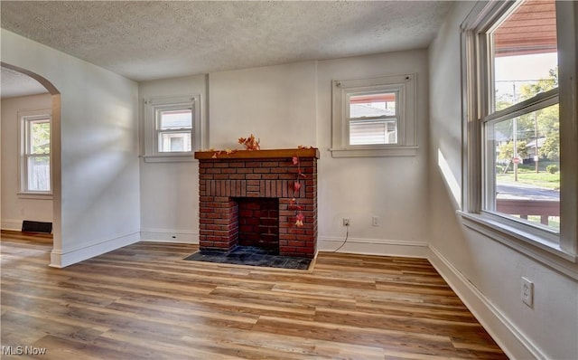 unfurnished living room featuring a fireplace, a wealth of natural light, and wood-type flooring