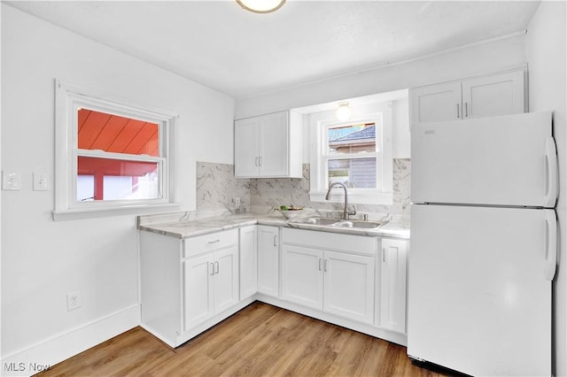 kitchen with white refrigerator, white cabinetry, sink, and a wealth of natural light