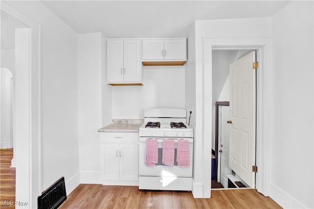 kitchen featuring white cabinetry, white range with gas stovetop, and light wood-type flooring