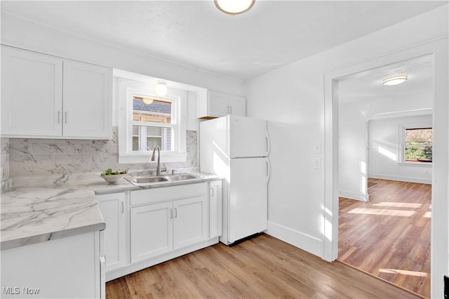 kitchen with backsplash, sink, white fridge, and white cabinets