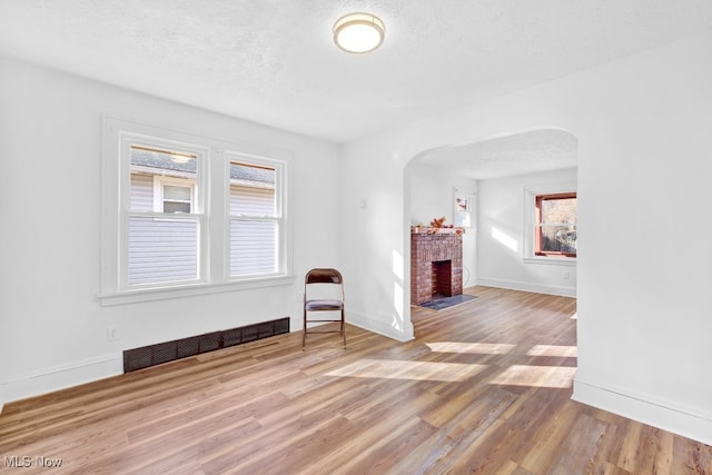 interior space featuring a brick fireplace, hardwood / wood-style floors, and a textured ceiling