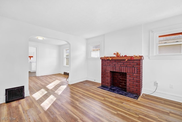 unfurnished living room with a brick fireplace and light hardwood / wood-style floors