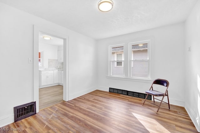 unfurnished room with light hardwood / wood-style flooring and a textured ceiling