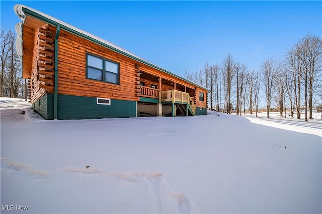 snow covered rear of property featuring a deck