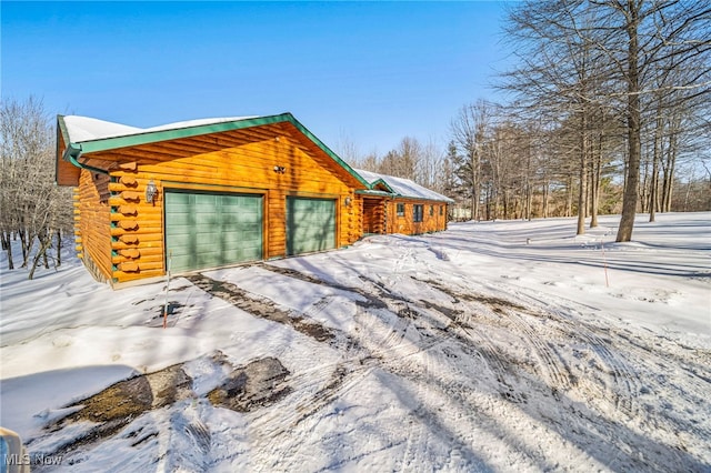 view of snow covered exterior featuring a garage and an outdoor structure