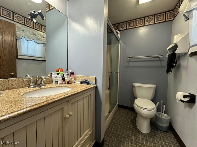 bathroom featuring tile patterned floors, toilet, a shower with shower door, and vanity