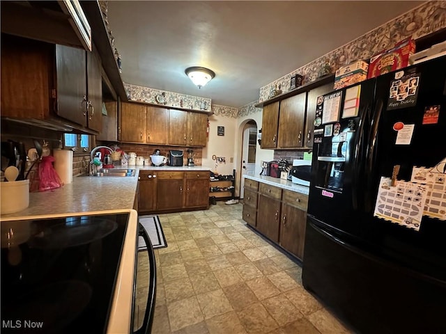 kitchen with black refrigerator, tasteful backsplash, sink, electric range, and dark brown cabinets