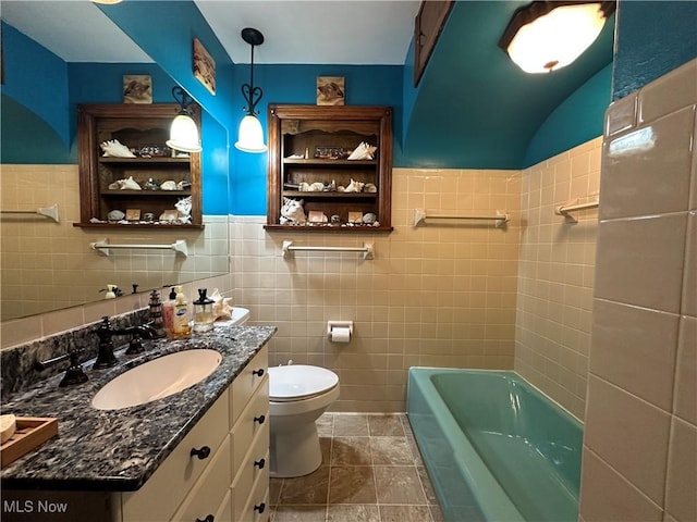 bathroom with tile walls, a bathing tub, vanity, tile patterned floors, and toilet