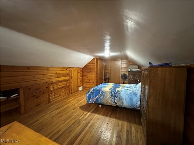 bedroom featuring hardwood / wood-style flooring, lofted ceiling, and wood walls