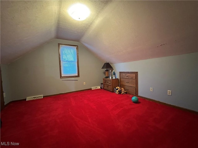 additional living space featuring lofted ceiling, carpet, and a textured ceiling