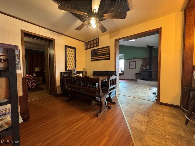 misc room with hardwood / wood-style flooring, ceiling fan, and a wood stove