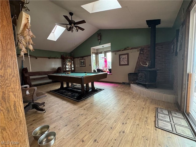 recreation room with lofted ceiling, hardwood / wood-style flooring, ceiling fan, and a wood stove