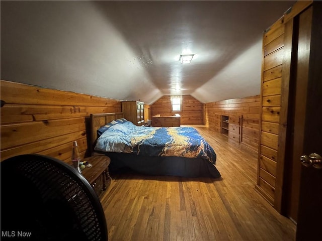 bedroom with hardwood / wood-style flooring, lofted ceiling, and wooden walls