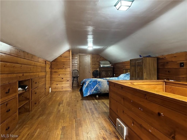 bedroom featuring lofted ceiling, wood-type flooring, and wood walls