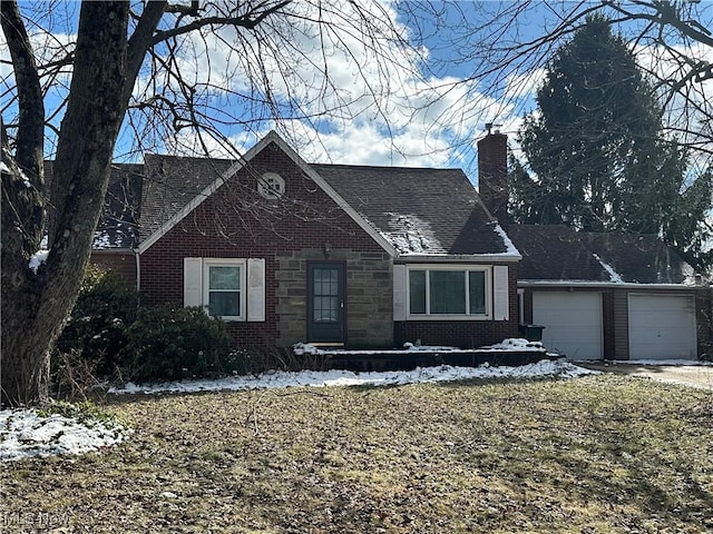 view of front facade featuring brick siding, stone siding, a chimney, and a garage