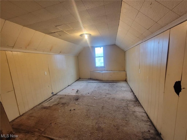 additional living space with wooden walls and vaulted ceiling