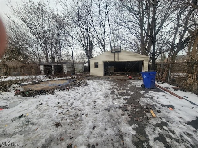 yard layered in snow featuring an outbuilding and a garage