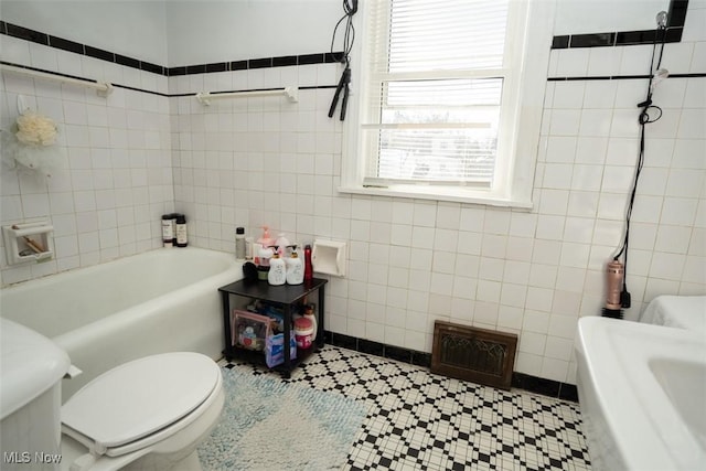 bathroom featuring a washtub, tile walls, and toilet