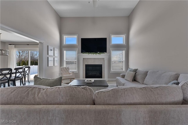 living room featuring a tile fireplace, plenty of natural light, and a towering ceiling