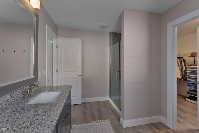 bathroom with vanity, a shower with shower door, and wood-type flooring