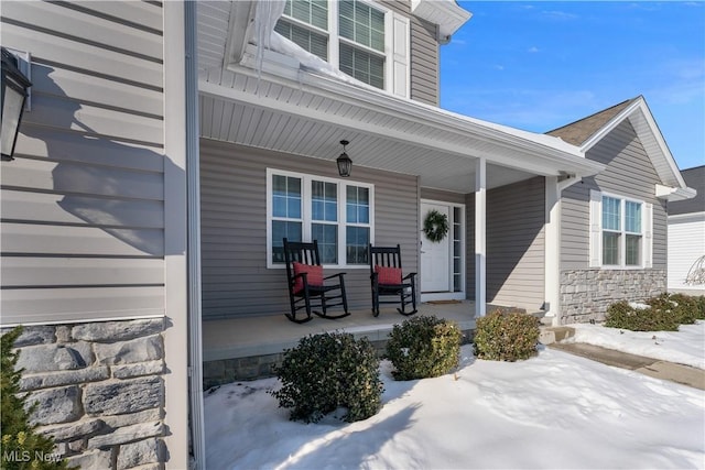 snow covered property entrance featuring a porch