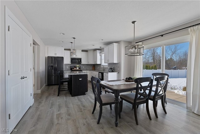 dining space featuring sink, a textured ceiling, and light wood-type flooring