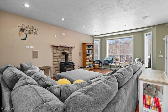 living room with hardwood / wood-style flooring, a textured ceiling, and a wood stove