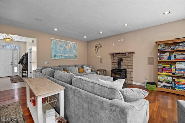 living room with a wood stove, a textured ceiling, and dark hardwood / wood-style flooring