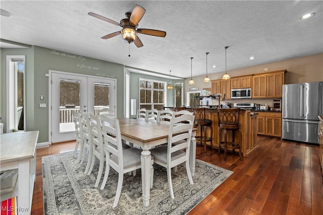 dining area with ceiling fan, dark wood-type flooring, french doors, and a textured ceiling