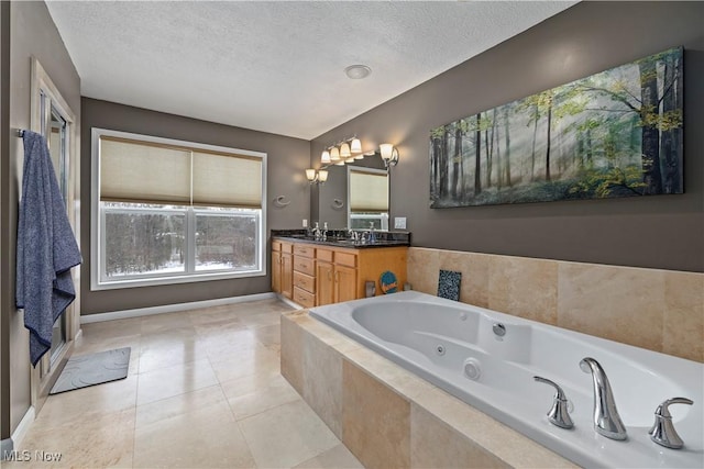 bathroom with tile patterned flooring, vanity, tiled bath, and a textured ceiling