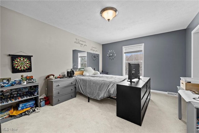 bedroom featuring multiple windows, light carpet, and a textured ceiling