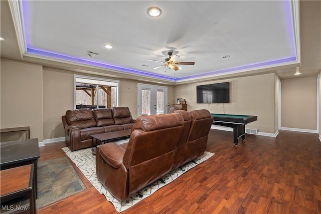 living room featuring a raised ceiling, dark wood-type flooring, and french doors