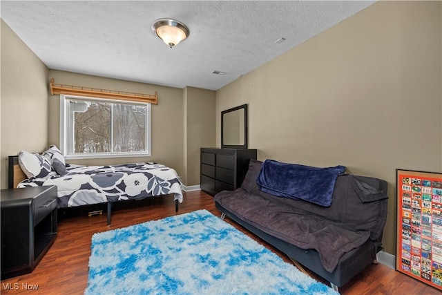 bedroom with dark hardwood / wood-style flooring and a textured ceiling