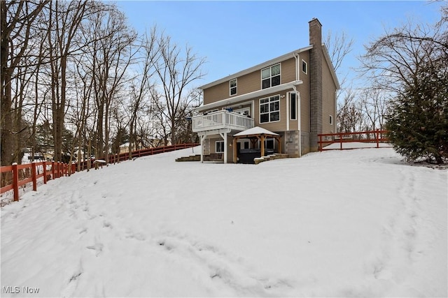 snow covered back of property with a balcony