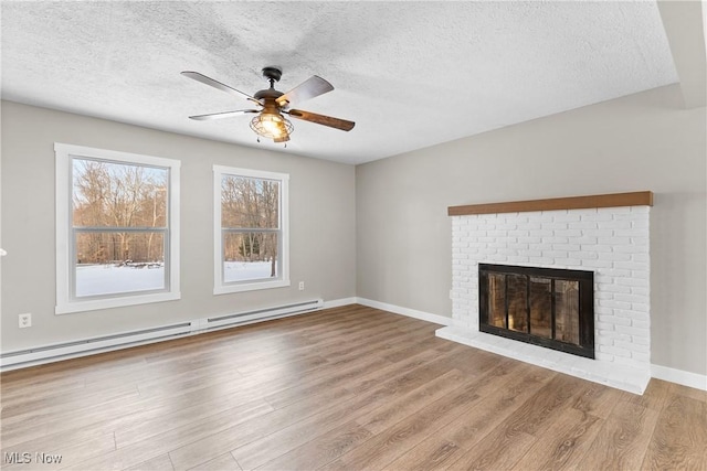 unfurnished living room with ceiling fan, baseboard heating, light hardwood / wood-style floors, a textured ceiling, and a brick fireplace